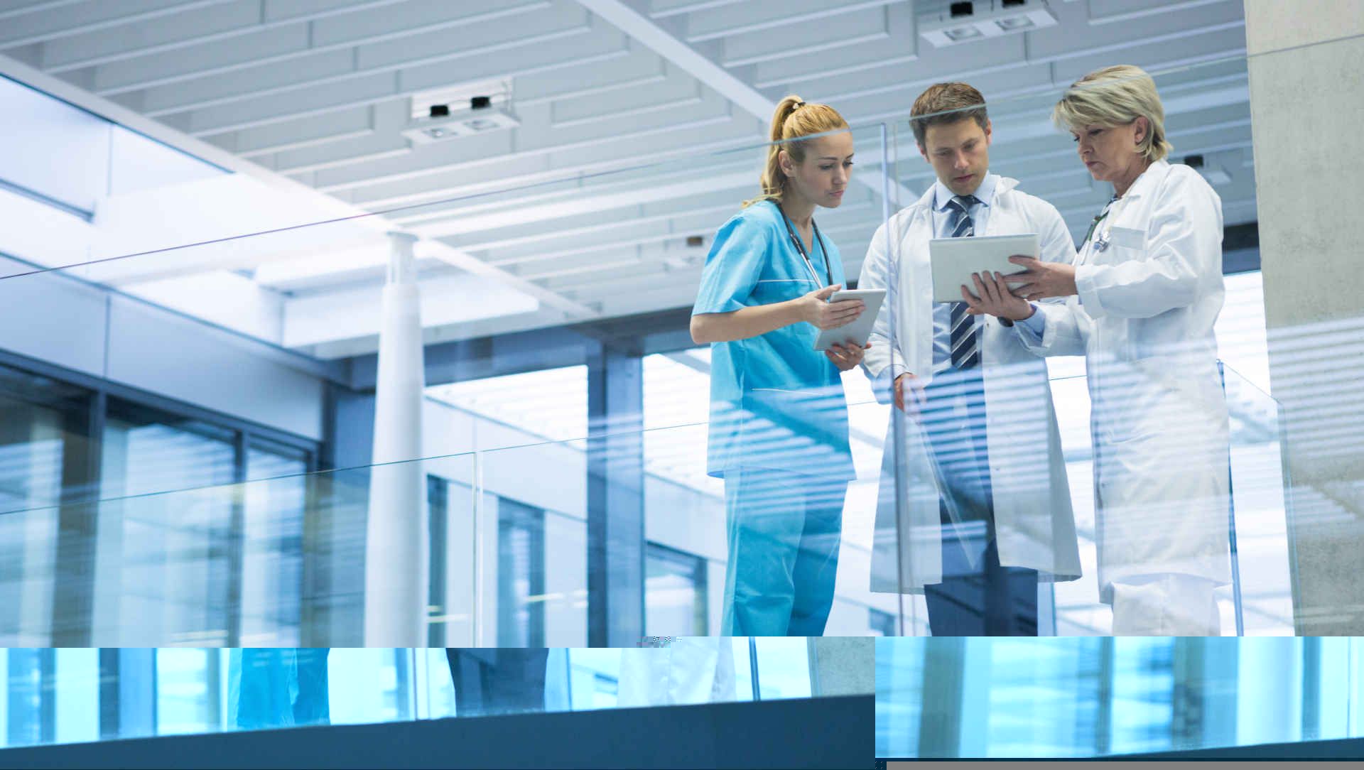 Three doctors reading from a tablet in the corridor